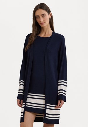 Navy cardigan with long sleeves, open front, and white stripe accents on sleeves and hem. Made from soft, textured fabric.