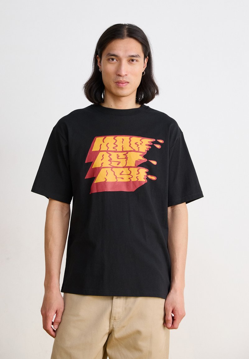 Black cotton t-shirt featuring a large yellow and red graphic print with a dripping effect, short sleeves, and a relaxed fit.