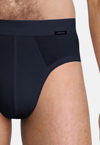 Mörkblå herrkalsonger, tillverkade av mjukt stretchmaterial, med en slät midjeband och en liten logotagg, utformade för komfort och passform.