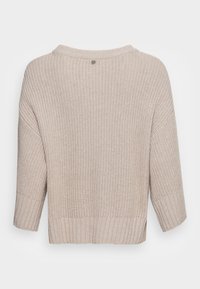 Maglione lavorato a maglia di un beige chiaro, con una vestibilità ampia, orlo e polsini a coste, e un dettaglio con bottone sul retro. Tessuto testurizzato con un design rilassato.
