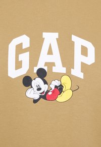 Brązowa bluza z dużym białym napisem "GAP" oraz kolorową grafiką Myszki Mickey trzymającej czerwony przedmiot, o gładkiej fakturze.