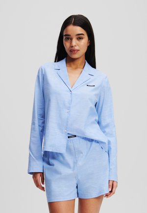 Ensemble de pyjama bleu clair comprenant une chemise à boutons avec col et un short assorti, fabriqué en tissu doux et texturé. Détail de logo subtil inclus.