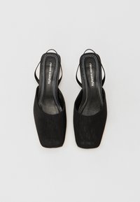 Fekete slingback magassarkú cipők, négyzet alakú orral, sima anyagból készült, kontrasztos fehér varrással és vékony sarkú kialakítással.