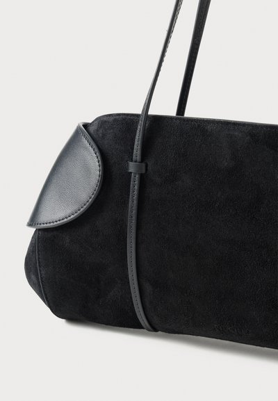 Sort ruskind skuldertaske med en buet læderklap, en slank skulderrem, en glat overflade og minimalistiske designdetaljer.