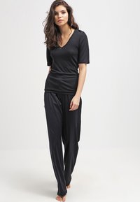 Top nero a scollo a V con maniche corte abbinato a pantaloni neri larghi. Tessuto morbido e liscio con una silhouette rilassata. Senza motivi o dettagli.