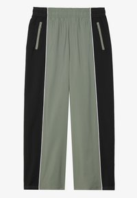 Athletic joggers with an elastic waistband, featuring a black and olive green color block design, zippered side pockets, and white accents.