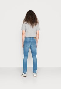 Lichtblauwe jeans met een slim fit en een lichte stretch, voorzien van een klassieke vijf-pocket ontwerp en een bruin leren label op de tailleband.