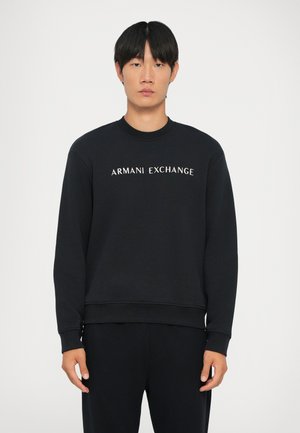 Sudadera negra con mangas acampanadas y cuello de canalé. Presenta el logo "ARMANI EXCHANGE" en blanco en el pecho. Material suave.