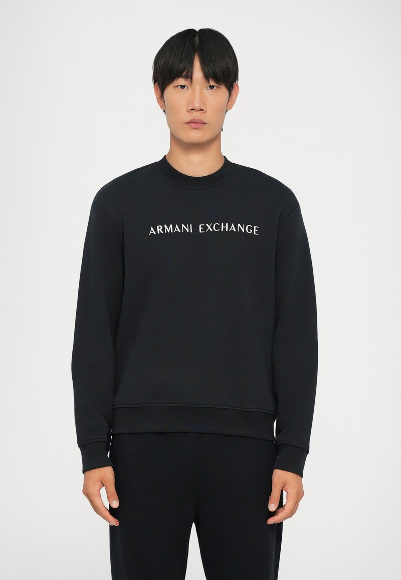 Felpa nera con maniche a costine e colletto a coste. Presenta il logo "ARMANI EXCHANGE" in bianco sul petto. Materiale morbido.