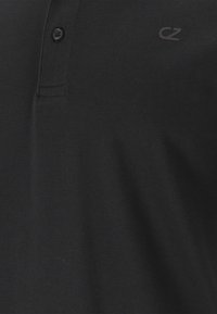Sort polo-shirt lavet af struktureret stof, med en to-knaps placket og et lille logo i mørkegrå på det øverste venstre hjørne.