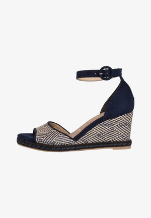 Navy blue wedge sandal with woven patterned straw upper, open toe, ankle strap with buckle, and braided jute sole.