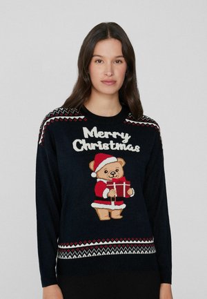 Pull marin avec un motif de tricot festif rouge et blanc, comprenant un ours brodé en tenue de Santa tenant un cadeau et le texte "Joyeux Noël".
