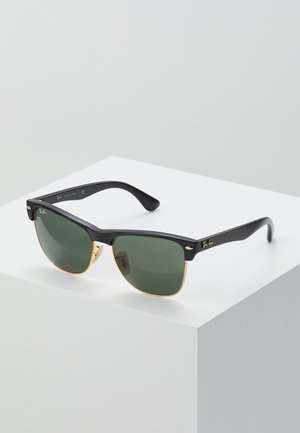 Ray-Ban-solglasögon med gröna linser, svarta plastbågar och gyllene detaljer vid kanterna. Fyrkantig form med en matt yta.