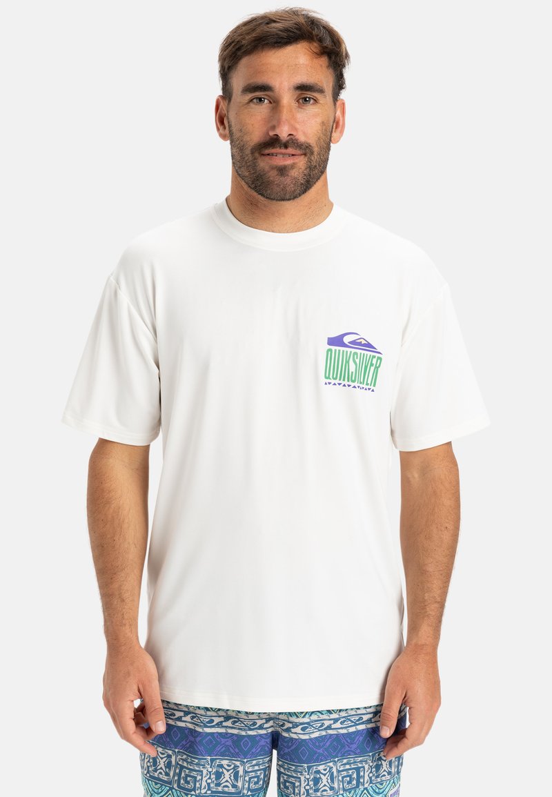 Camiseta blanca de mangas cortas confeccionada en una tela suave, con un logotipo colorido de Quiksilver en el lado izquierdo del pecho. Corte relajado y cuello redondo.