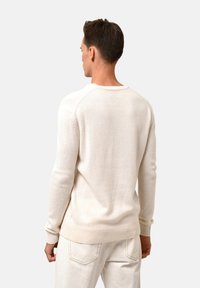 Helle beigefarbene Strickjacke aus weichem Material, mit rundem Halsausschnitt, gerippten Bündchen und Saum, slim fit und langen Ärmeln.