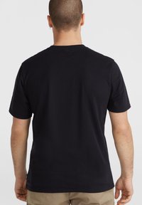Juodas medvilninis T-shirt su trumpomis rankovėmis, standartinio kirpimo ir klasikinio apvalaus iškirpimo. Paprastas dizainas be matomų grafikos ar raštų.