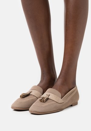 Mocassini beige con una trama intrecciata e dettagli in suede. Presentano delle nappine decorative sulla parte anteriore e una suola piatta e flessibile.