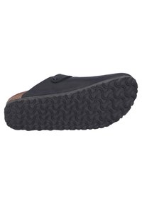 Black slip-on shoe with a smooth upper material, cork insole, and textured rubber outsole featuring a wavy pattern. Includes a round button accent.