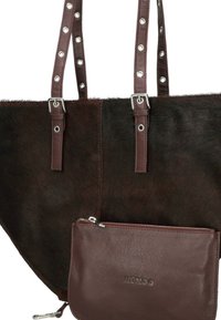 Sac fourre-tout en cuir marron avec un devant en fourrure sombre, quincaillerie en argent et deux sangles cloutées. Comprend une pochette zippée détachable en cuir marron.