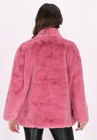 Giacca in pelliccia sintetica di un vivace rosa, con colletto alto, vestibilità ampia e maniche lunghe. Tessuto morbido con superficie liscia.