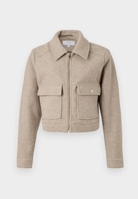 Cropped beige jacket made of textured fabric, featuring a zipper front, point collar, and two front flap pockets with gold buttons.