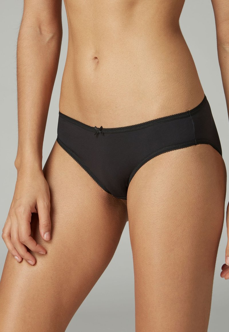 Black cotton brief with a smooth texture, featuring a delicate lace trim and a small bow detail at the front. Mid-rise design.