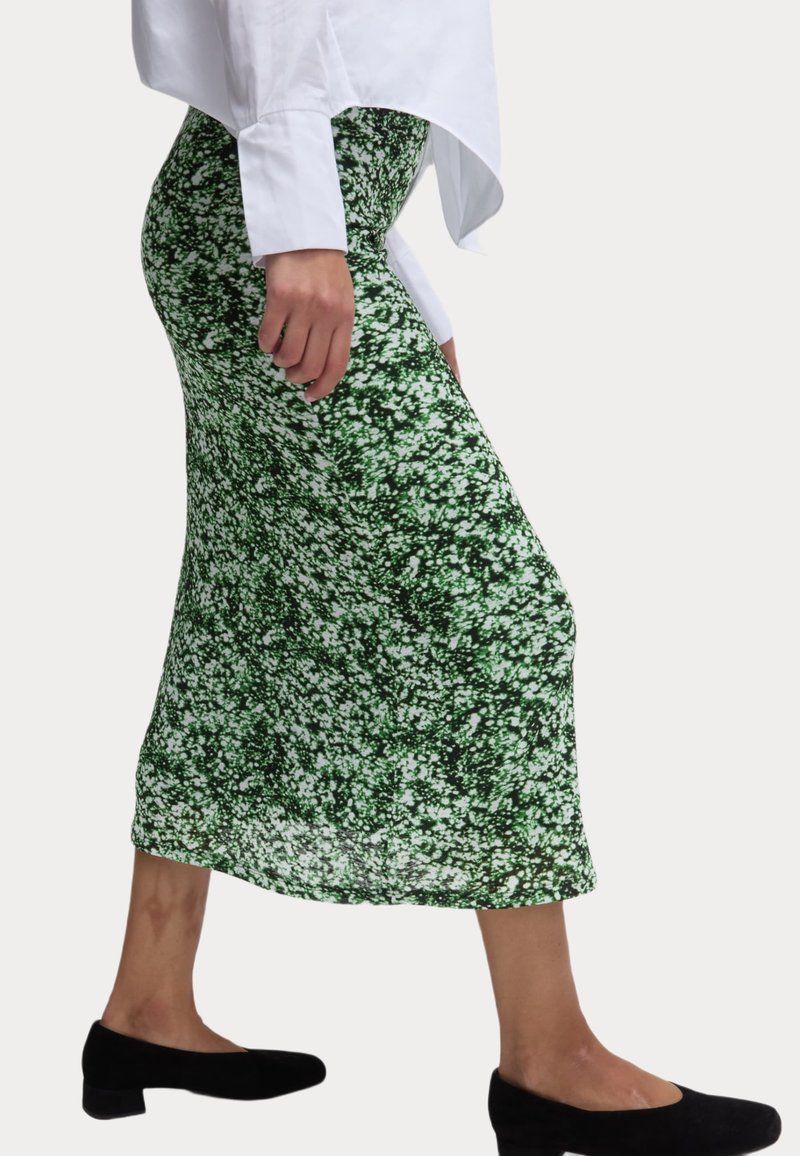 Jupe maxi imprimée verte en tissu léger, ornée d'un motif floral blanc dispersé, avec une taille ajustée et une forme fluide.