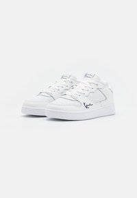 White athletic shoes with a perforated texture, blue accents, and laces. Features a padded collar and a flat rubber sole.