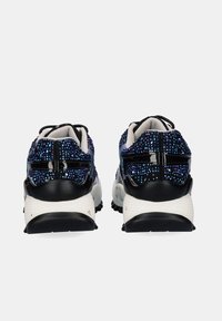 Un par de zapatillas negras con detalles de purpurina azul, suelas blancas acolchadas y suelas de goma negras, vistas desde la parte trasera.