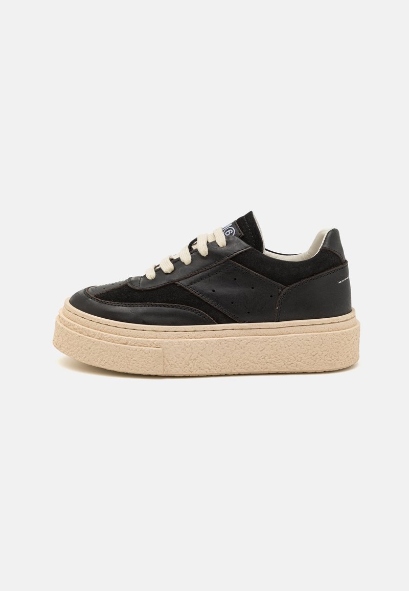 Baskets basses noires avec semelle épaisse beige et lacets blancs, avec des panneaux en cuir et en daim mélangés et de subtils trous de ventilation.