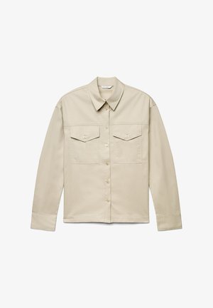 Chemise beige à manches longues avec boutons sur le devant, deux poches poitrine à rabat avec boutons, et un col classique.