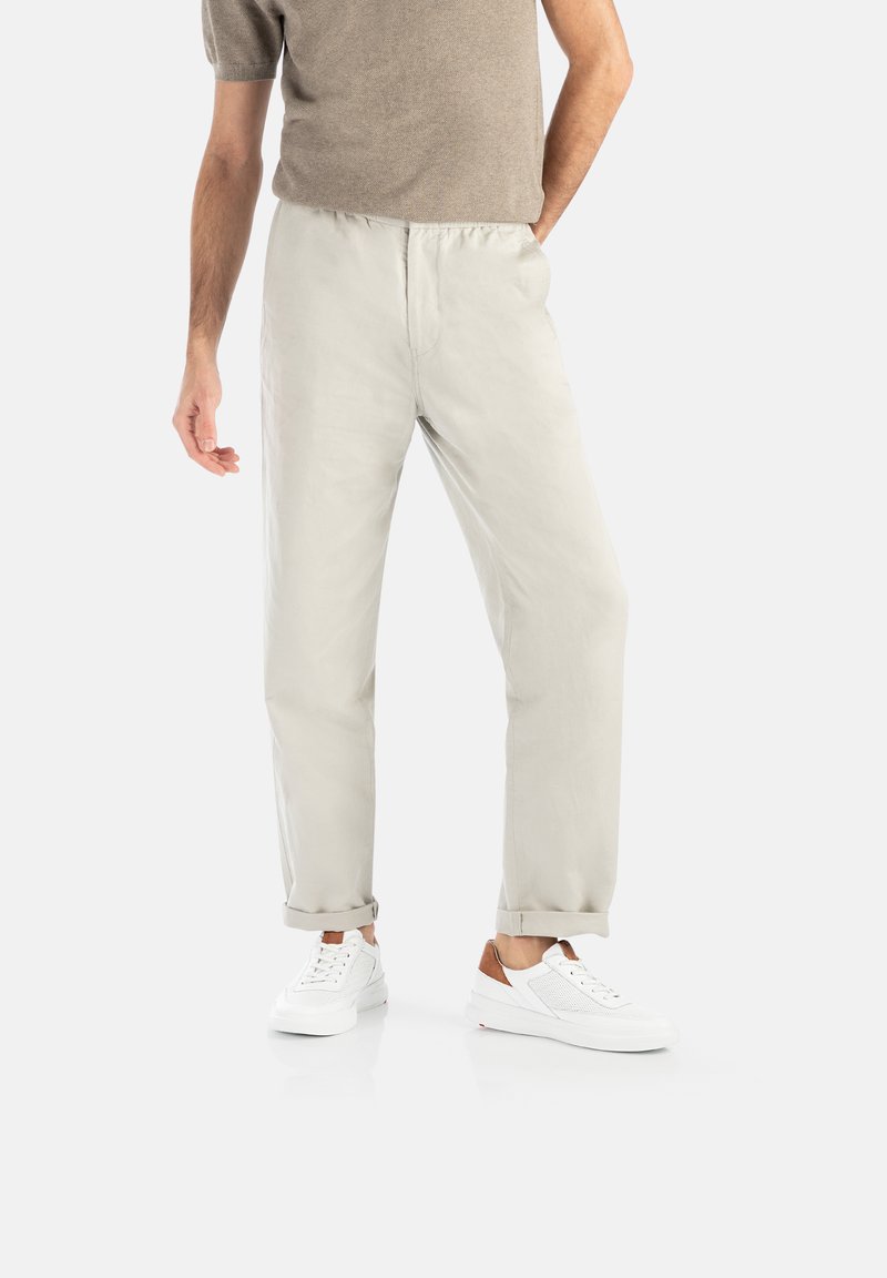 Jasnoszare, lekkie spodnie z elastycznym pasem, lekko zwężanym krojem, z podwiniętymi mankietami, w zestawie z białymi trampkami z brązowymi akcentami.