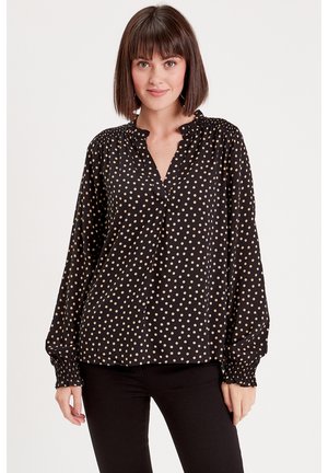 Schwarze Bluse mit langen Ärmeln und beige gepunktetem Muster, mit V-Ausschnitt und gerafften Manschetten für eine entspannte Passform.