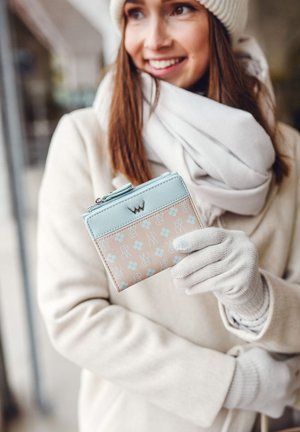 Light blue and beige wallet with floral patterns and initials, featuring a zip closure and silver hardware, held by a person in a white coat.