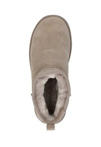 Beige suède enkellaars met zachte bontvoering, ronde neus en een lus aan de achterkant voor gemakkelijk aan- en uittrekken. Platte zool, minimalistisch ontwerp.