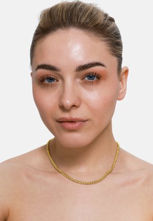 Goldene Kettenhalskette mit miteinander verbundenen Gliedern, glatter Textur und polierter Oberfläche, die auf nackter Haut ruht und dezent glänzt.