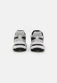 Buty sportowe w czarno-białej kolorystyce, z siateczkową cholewką, amortyzowaną podeszwą, przezroczystymi akcentami oraz teksturowaną czarną podeszwą.