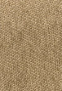 Beige kootud kangas tekstureeritud pinnaga, millel on tihe kude ja peened värvi variatsioonid, mis annavad loomuliku, maanäo.