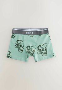 Pantaloni boxer verde menta con motivo di teschi neri e cuffie; la cintura elastica grigia presenta la parola "NEXT" in bianco. Tessuto dalla consistenza morbida.