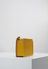 Borsa gialla in pelle con forma rettangolare, texture liscia e rifiniture grigie a contrasto. Dotata di cerniera per la chiusura e manico superiore.