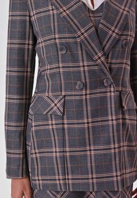 Grau kariertes Blazer mit doppelt geknöpftem Design, orange und weißen Streifen, zwei vorderen Taschen undreversierter Kragen. Strukturierter Stoff.