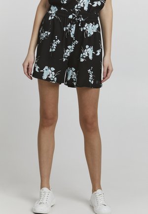 Svart blomstershorts med lys blå blomstermønster, elastisk midjebånd og en avslappet passform, paret med hvite sneakers.