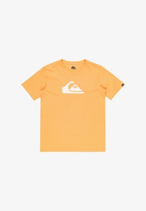 Camiseta de algodón naranja con logo blanco, combinada con pantalones cortos verde oliva, zapatillas en blanco y negro, y calcetas negras hasta la rodilla.