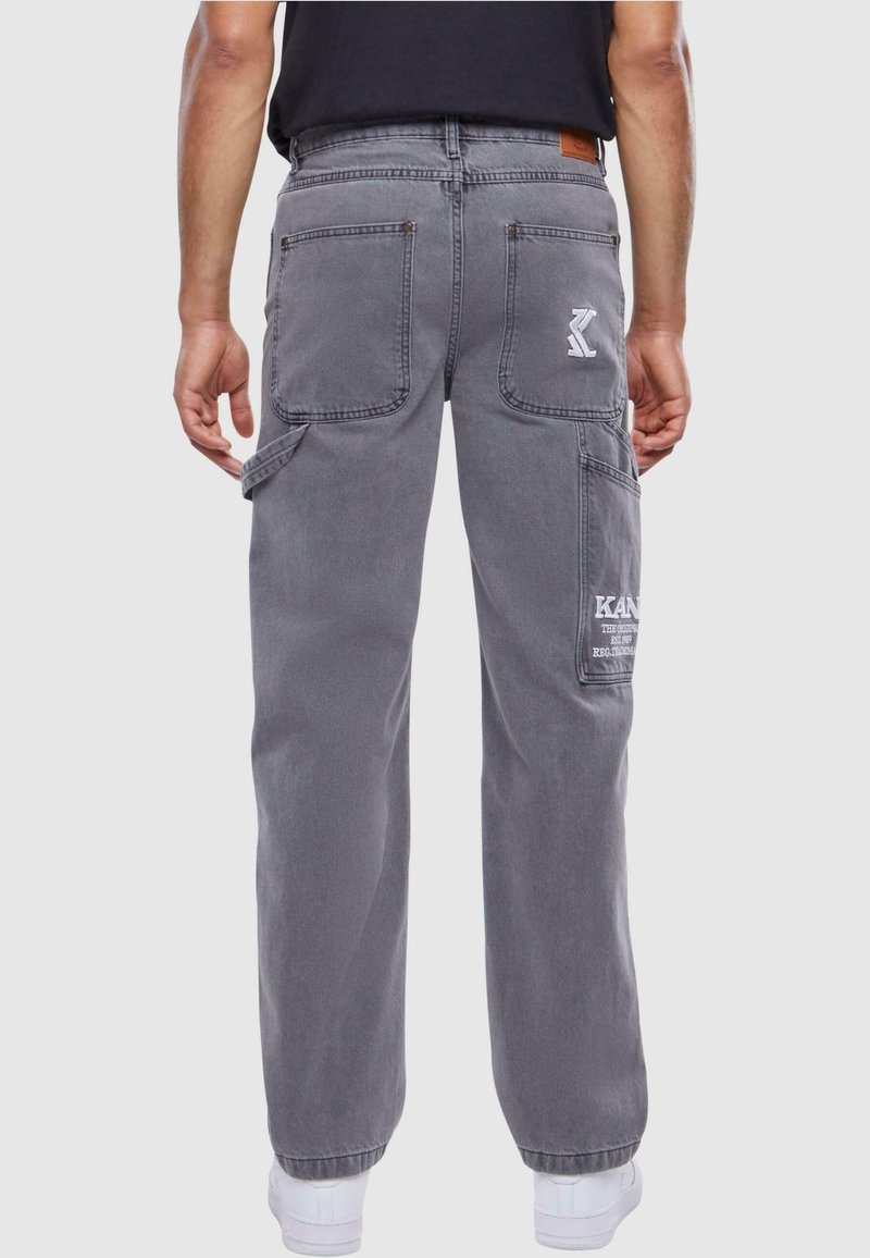 Pantalons cargo gris avec plusieurs poches, coutures visibles et un patch logo. Fabriqués en tissu doux et durable avec une coupe décontractée.