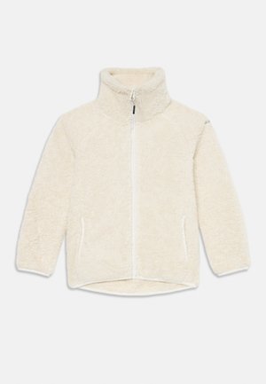 Veste en polaire de couleur crème, avec un col montant, une fermeture éclair à l'avant, des poches latérales et un tissu doux et texturé.