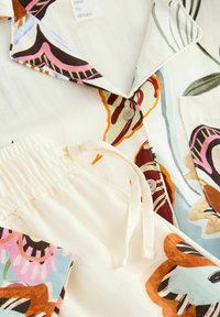 Pajama set featuring a floral pattern in shades of pink, brown, and green on soft, light fabric. Includes a collared top and elastic-waist pants.