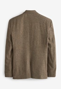 Pruun tweed jakk, millel on herringbone muster, üks avaus ja kaelus kergelt lõigatud. Tekstureeritud kangas struktureeritud siluetti.