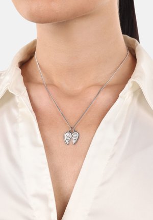 Collarín blanco, se lleva un collar con un colgante de corazón roto de plata que tiene grabados "Te amo" y "Me amas".