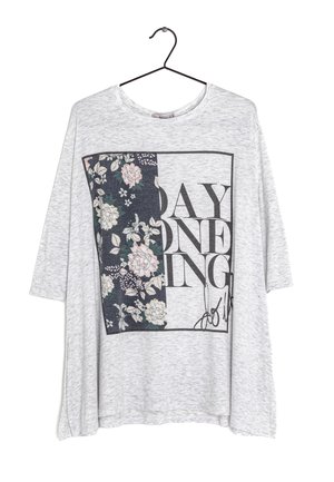 Chemise gris clair à manches longues avec un motif rectangulaire floral et un texte disant "SAY ONE ING" en lettres noires, suspendue à un cintre noir.