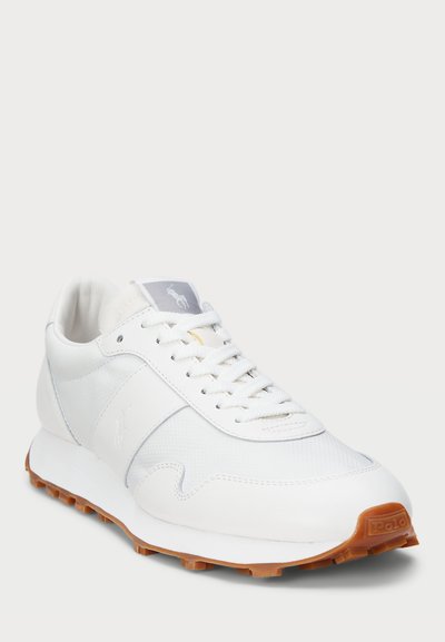 Baltos sportinės batai su lygia oda ir tekstūruotu tinkleliu viršuje. Yra guma, suteikianti sukibimą, raištelių užsegimas ir logotipo akcentas ant liežuvėlio.